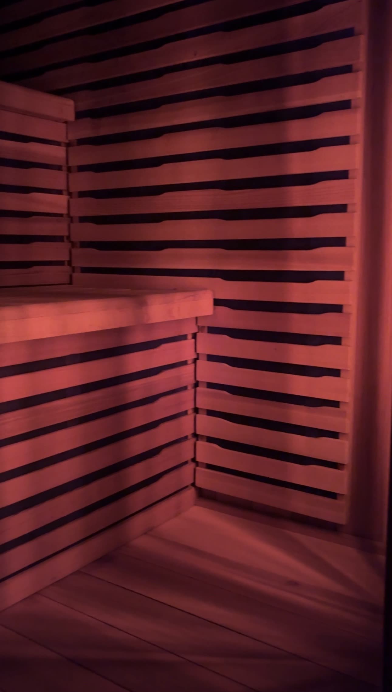 Empty cedar sauna bench in warm red light