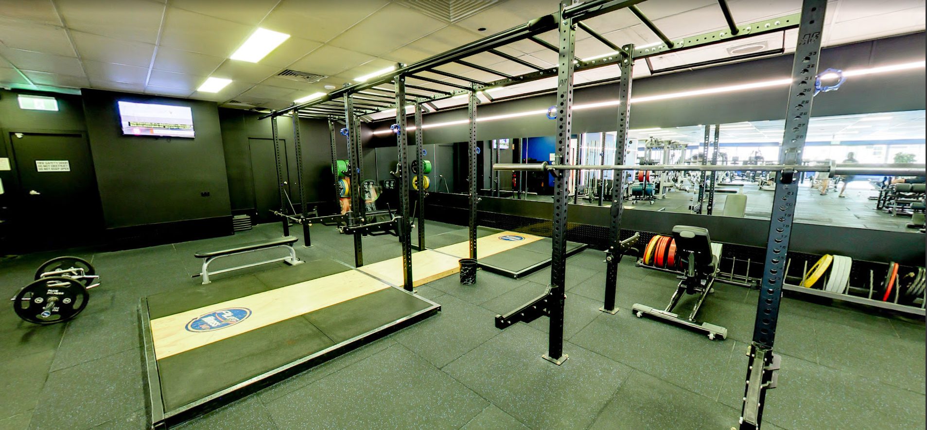 Squat racks and a wooden lifting platform with bumper plates